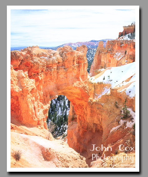 An arch frames the snow covered landscape surrounding Bryce Canyon National Park in Utah.