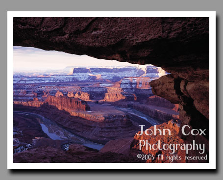 The Colorado River winds through a gooseneck beneath snow-covered cliffs from Dead Horse Point in Utah.